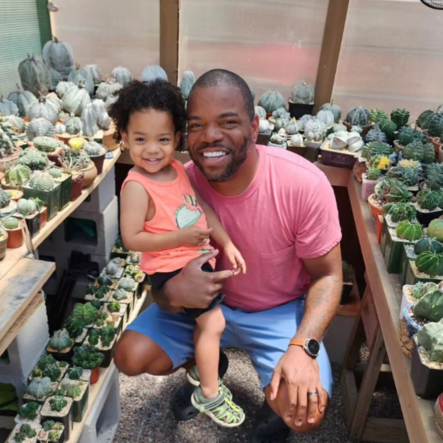 Adam Baker and his daughter in his greenhouse surrounded by cacti.